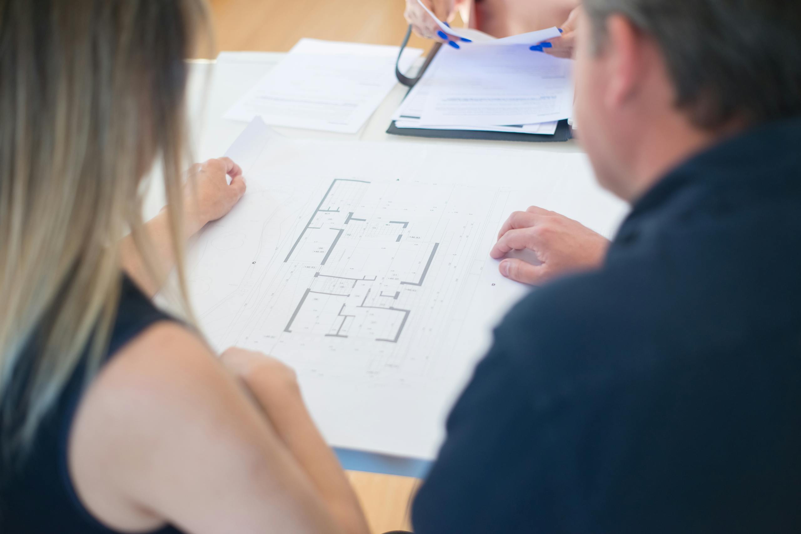 Back View of Man and Woman Looking at Floor Plan