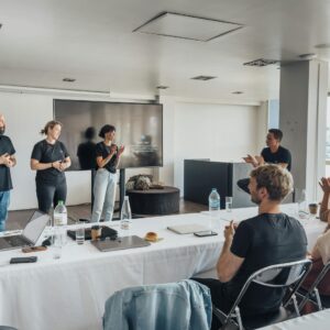 Team members presenting in a modern office with colleagues applauding.